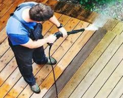 A person cleaning a wooden fence