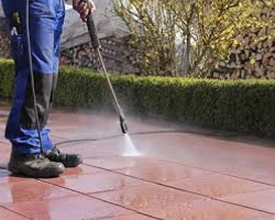 A person power-washing a porch